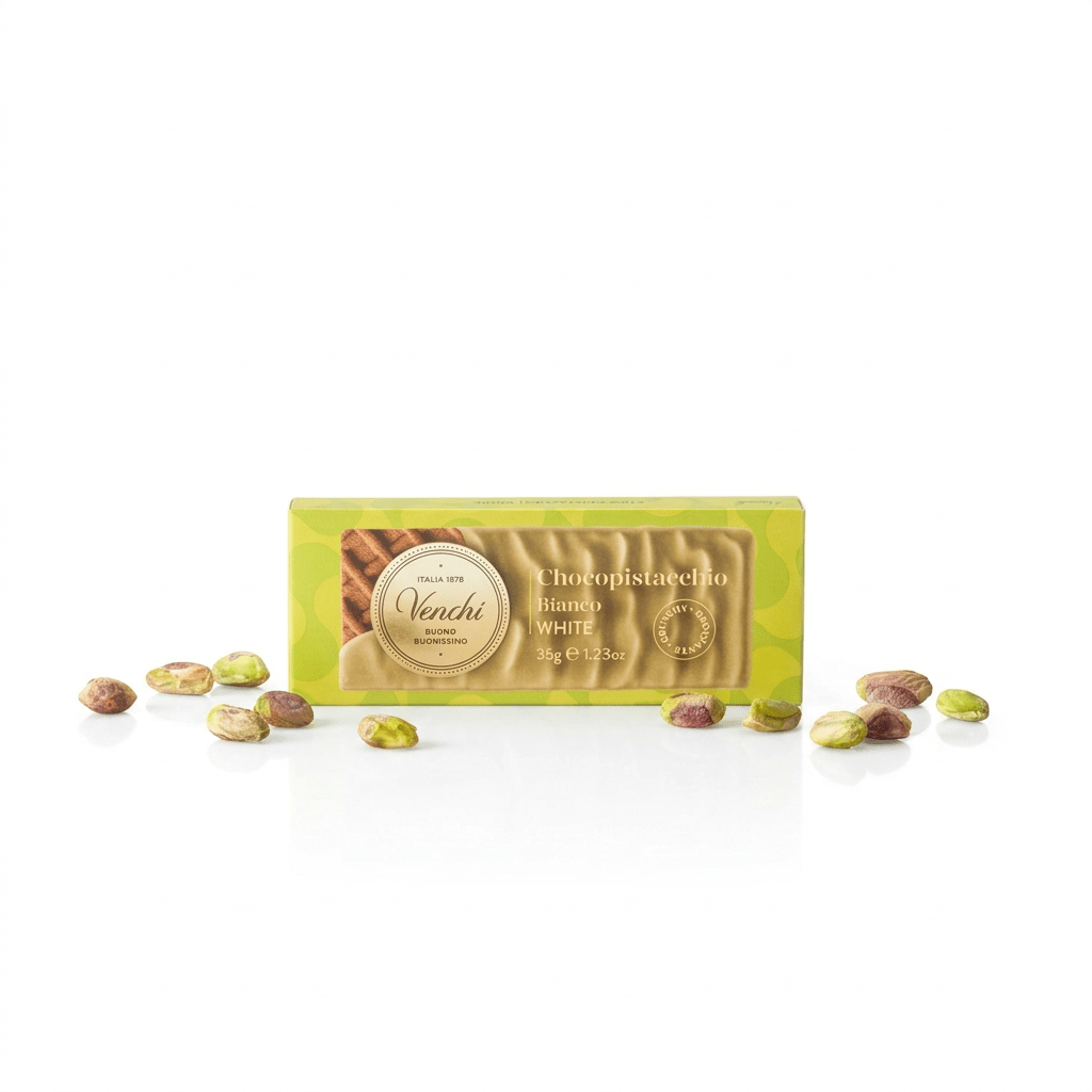 A rectangular box of Venchi Chocopistacchio Pistachio White chocolate bars sits centered on a white background, with several whole and shelled pistachios scattered around it.