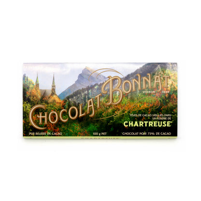 A 100g bar of Chartreuse Chocolat Bonnat chocolate, featuring a scenic landscape illustration of a mountain village with a church on the wrapper, set against a plain white background.