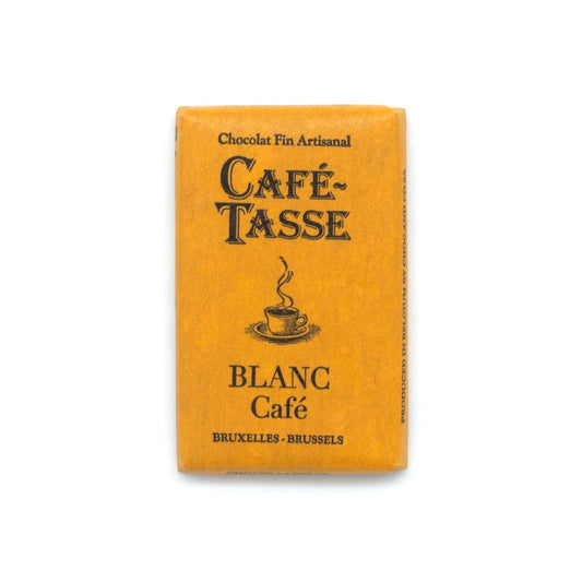 A rectangular package of Café Tasse Blanc Café chocolate, featuring a textured yellow wrapper with black printed text and a coffee cup illustration, set against a plain white background.