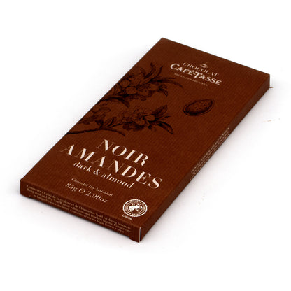 A chocolate bar package from Cafe-Tasse, featuring a dark brown box with embossed floral designs and the text 'Noir Amandes dark & almond' on a white background.