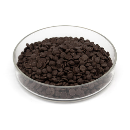 Dark chocolate chips in a clear glass bowl on a white background.