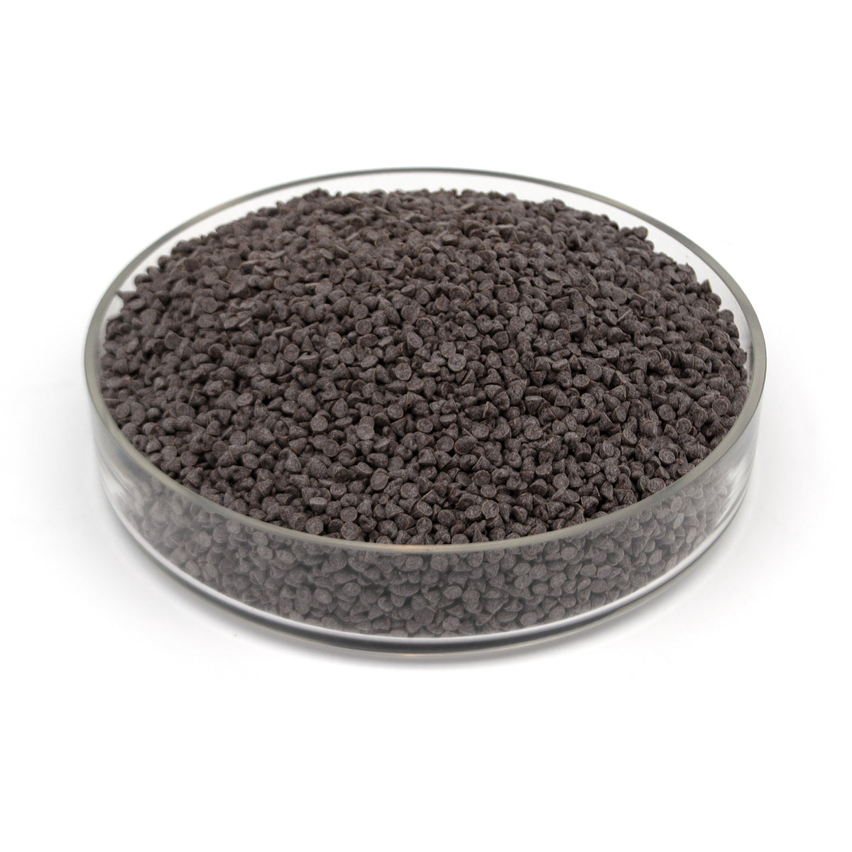 A glass dish full of small dark chocolate chips photographed on a white background.