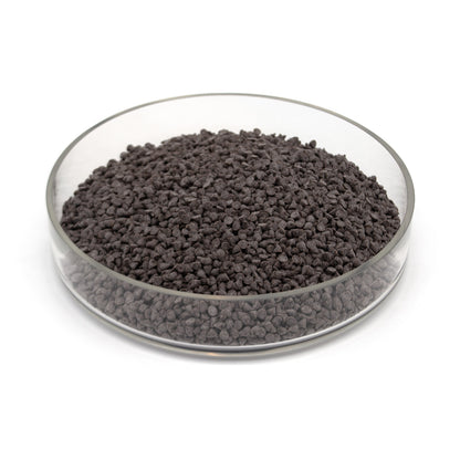 A glass dish half full of small dark chocolate chips photographed on a white background.
