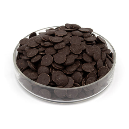 A pile of dark chocolate wafers in a clear glass bowl, photographed on a clean white background.