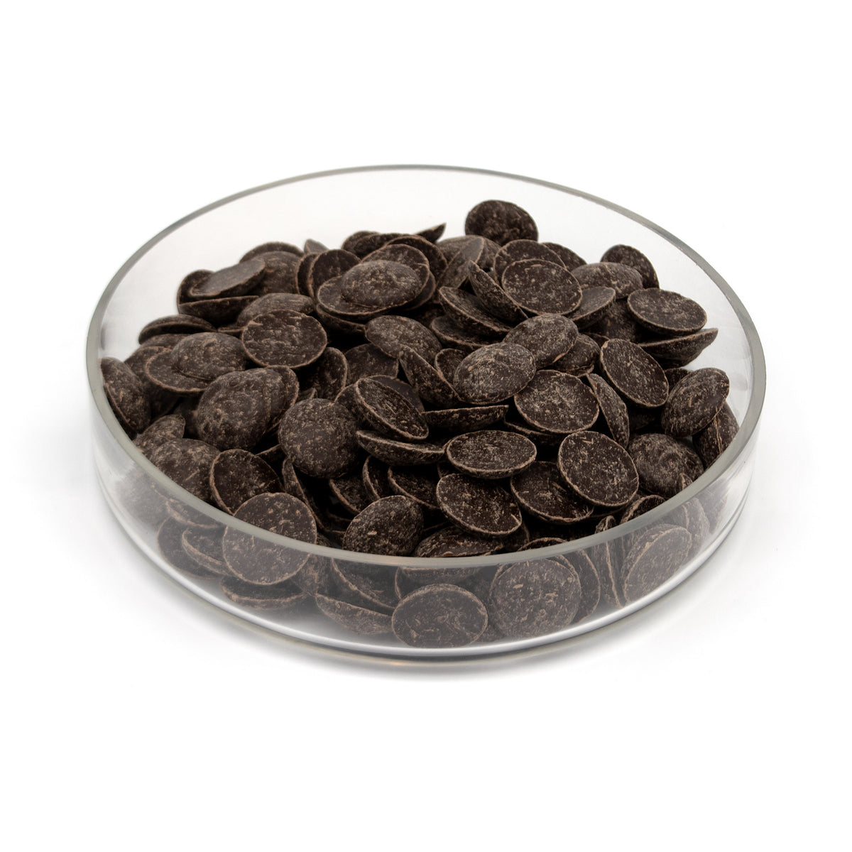 Glass bowl half filled with dark chocolate wafers on a white background