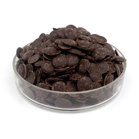 Glass bowl filled with dark chocolate wafers on a white background