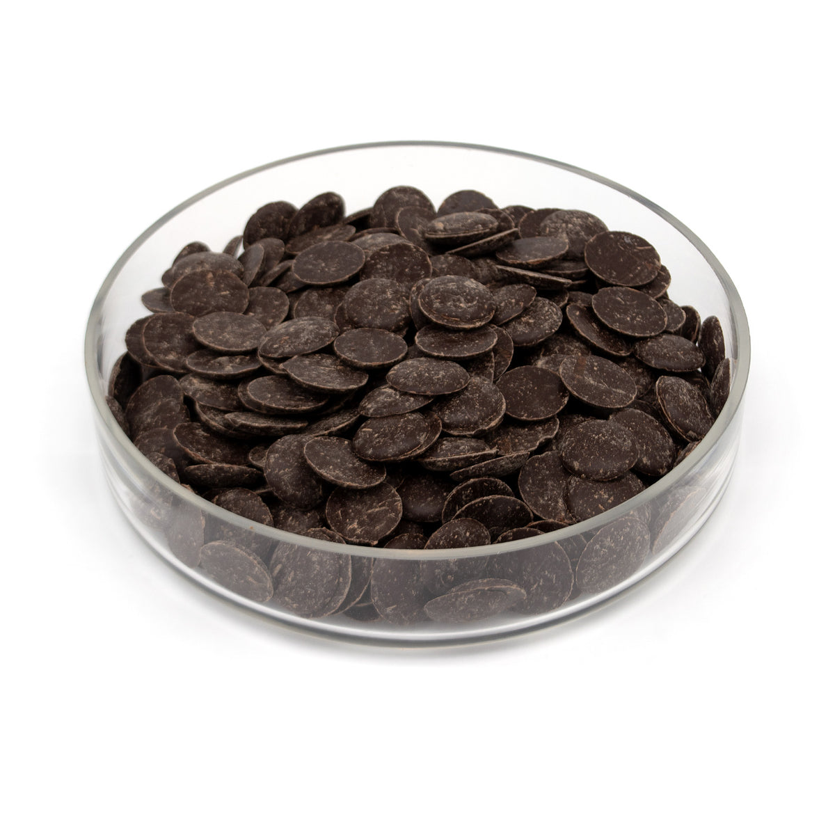Glass bowl half filled with dark chocolate wafers on a white background