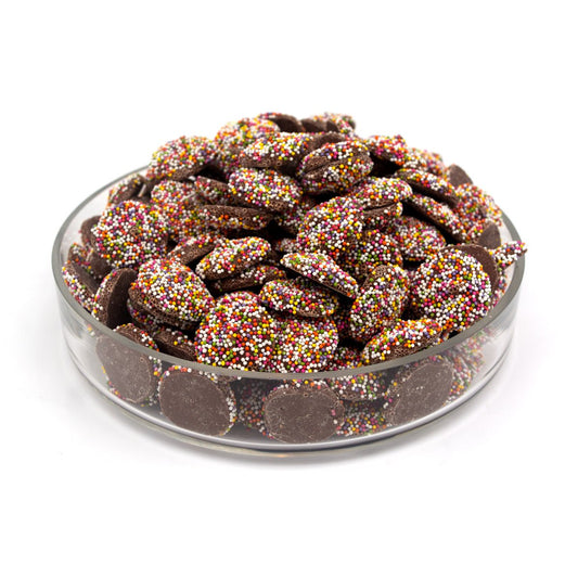 Glass bowl filled with chocolate covered wafers with colorful sprinkles on a white background