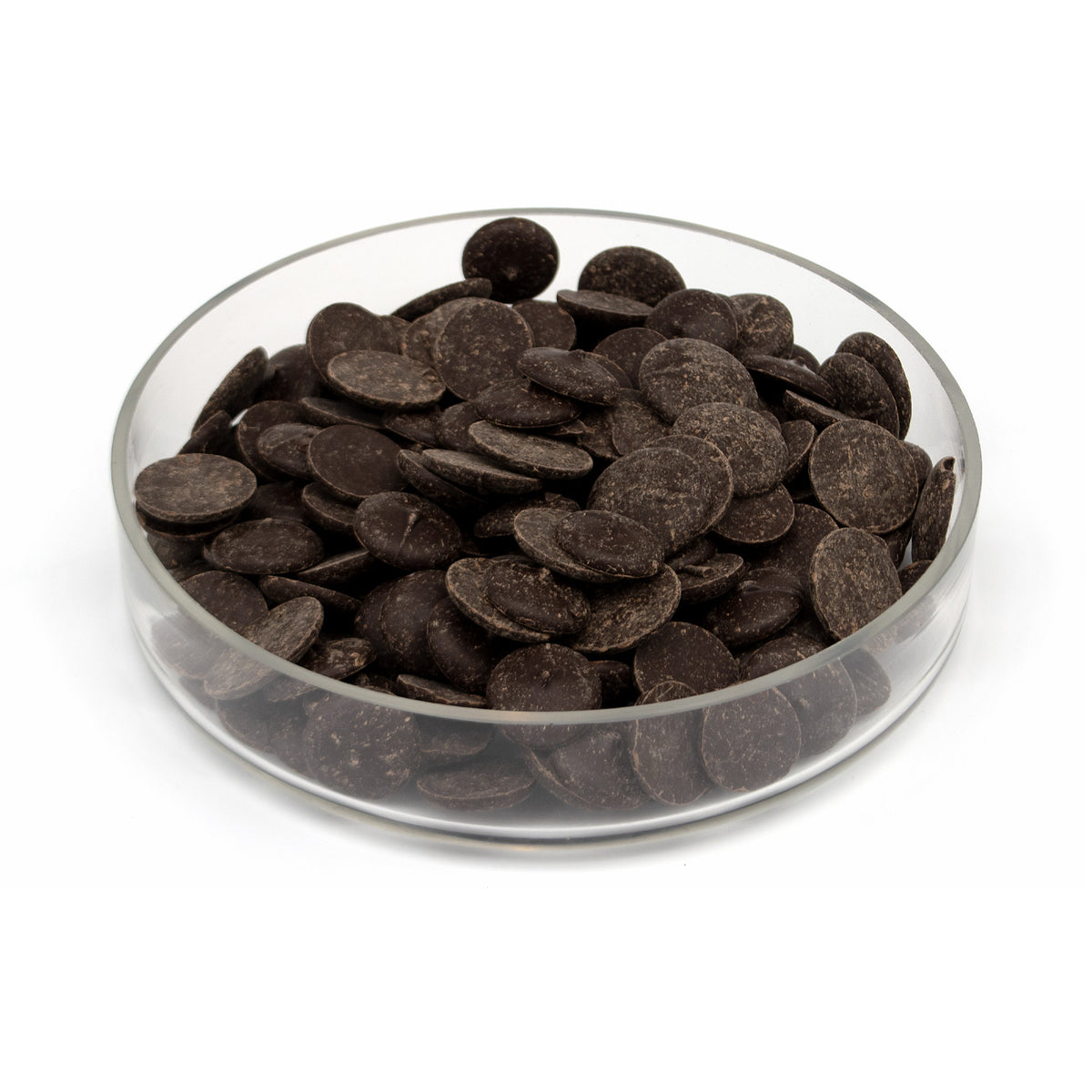 Dark chocolate wafers piled in a clear glass bowl on a white background.