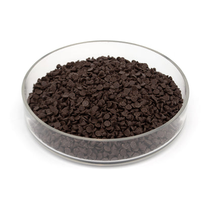 Glass bowl half filled with small dark brown chocolate chips on a white background