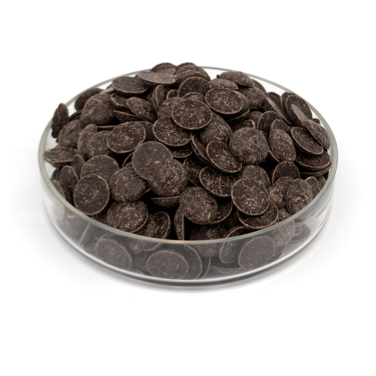 Dark chocolate wafers piled in a clear glass dish on a white background.