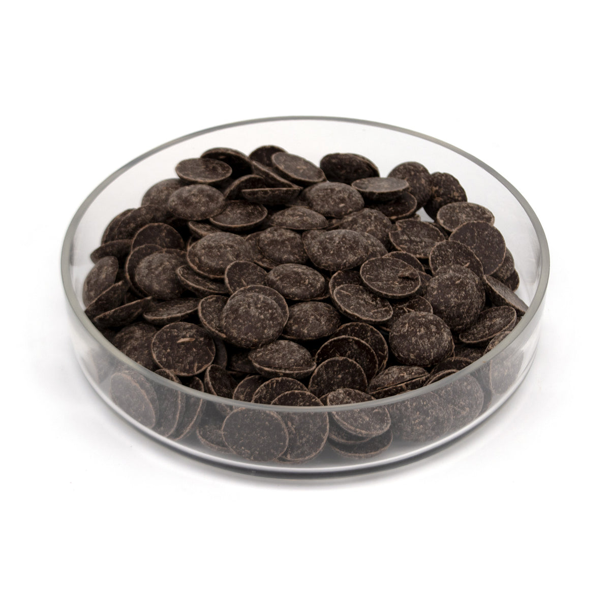 Dark chocolate wafers piled in a clear glass dish on a white background.