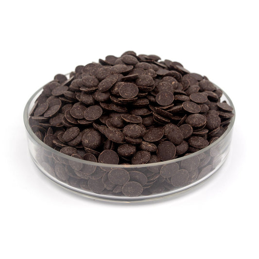 Glass bowl filled with dark chocolate wafers on a white background