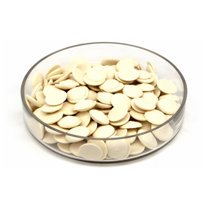 A clear round glass dish filled with small, flat, off-white disc-like pieces, photographed on a plain white background.