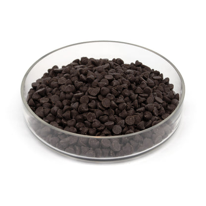 Dark chocolate chips in a clear glass bowl on a white background.
