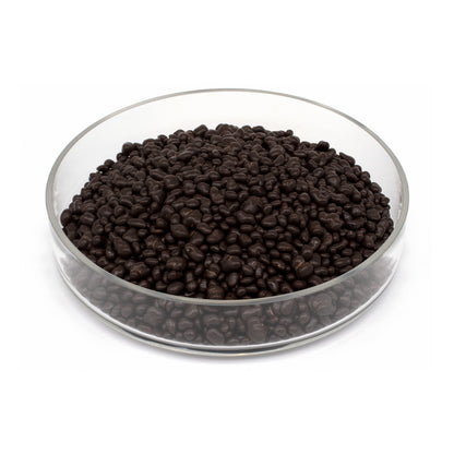 A pile of dark brown chocolate covered cacao nibs in a clear glass bowl, photographed on a plain white background.